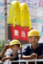 Chinese workers take a break in front of a MacDonalds' sign in Beijing Tuesday, Sept. 11, 2001.  Members of the World Trade Organization are meeting in Geneva this week in a bid to solve the final issues blocking China's 15-year bid to join the body which sets rules for international trade. (AP Photo/Ng Han Guan)