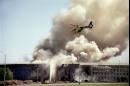 A helicopter flies over the Pentagon in Washington, Tuesday, Sept. 11, 2001 as smoke billows over the building. The Pentagon took a direct, devastating hit from an aircraft and the enduring symbols of American power were evacuated as an apparent terrorist attack quickly spread fear and chaos in the nation's capital. (AP Photo/Heenson Yim)