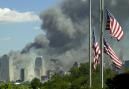 Flags fly at half-staff at the Liberty Science Center in Jersey City, N.J. as a large cloud of smoke billows from a fire at the World Trade Center in New York, Tuesday, Sept. 11, 2001.   In one of the most devastating attacks ever against the United States, terrorists crashed two airliners into the World Trade Center in a closely timed series of blows Tuesday that brought down the twin 110-story towers. (AP Photo/Daniel Hulshizer)