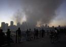 Pedestrians on Pierrepont Place in Brooklyn, N.Y., watch as smoke billows from the remains of the twin towers of the World Trade Center in New York, Tuesday, Sept. 11, 2001. (AP Photo/Lawrence Jackson)