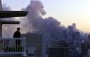 A man looks out from his apartment balcony as the smoke continues to rise from the World Trade Center as the sun sets over New York, Tuesday, Sept. 11, 2001. Gone from the New York City skyline is the two towers of the World Trade Center, they were destroyed by a terrorist attack early Tuesday morning. (AP Photo/Beth A. Keiser)