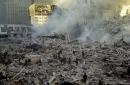 Firefighters walk through smoldering debris at the site of the World Trade Center in New York Tuesday, Sept. 11, 2001. Two planes crashed into the upper floors of both World Trade Center towers minutes apart Tuesday morning, collapsing the 110-story buildings. (AP Photo/Graham Morrison)