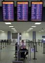 A security officer sits underneath monitors showing cancelled flights in the empty United States departure area at Pearson International Airport in Toronto Tuesday, September 11, 2001.  Repercussions from a devastating series of apparent terrorist attacks in the U.S. rippled across Canada on Tuesday as thousands of travellers were stranded at airports, offices were shut down and Canadian hospitals prepared to take in America's wounded. (CP PHOTO/Kevin Frayer)