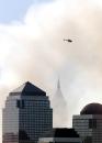 A helicopter flies through plumes of smoke still rising from the site of the World Trade Center in lower Manhattan, New York, Wednesday, Sept. 12, 2001. Twenty-four hours earlier, two hijacked airliners struck the towers and reduced them to rubble. (AP Photo/Jeff Zelevansky)