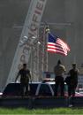 Military personnel walk past an American flag blowing in the wind at the Pentagon in Washington, D.C., Wednesday Sept. 12, 2001, as a construction crane in background helps with recovery efforts. The Pentagon was hit Tuesday by a terrorist-hijacked plane . (AP Photo/Steve Helber)