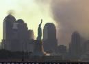 The Statue of Liberty stands in the early morning light in New York Harbor as smoke continues to rise from what is left of the World Trade Center towers in this view from Jersey City, N.J., Wednesday, Sept. 12, 2001. (AP Photo/Mike Derer)