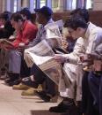 Jaime Merced, far right, of Jersey City, N.J., reads a paper while waiting at Newark Penn Station, N.J., for a New Jersery Transit train to New Brunswick, N.J., Wednesday, Sept. 12, 2001. Both New Jersey Transit and Port Authority Trans-Hudson (PATH) lines are running to New York. (AP Photo/Brian Branch-Price)