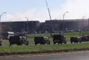 A convoy of U.S. Army troops arrived in in an effort to heighten security at the Pentagon Wednesday Sept. 12, 2001. Smoke rises as search and rescue teams worked in the remains of the portion of the Pentagon that collapsed on Tuesday after being hit by a hijacked jetliner. Officials said they doubted they would find any additional survivors, and said the number of deaths could reach into the hundreds. (AP Photo/Hillery Smith Garrison)