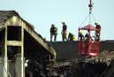 Firefighters, rear, stand along a roof line as inspectors in a basket look over the destruction at the Pentagon, Wednesday, Sept. 12, 2001. A hijacked airliner crashed into the structure on Tuesday. (AP Photo/Steve Helber)