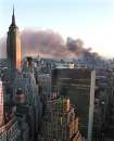 As the sun sets in Manhattan, New York City, smoke continues to pour from the sight of the World Trade Center in New York on September 11, 2001.  The World Trade Center towers were hit by hijacked commercial airplanes earlier in the day. The view is from midtown looking south.  The Empire State Building is at left.      REUTERS/Brad Rickerby