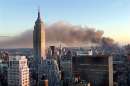 At dusk settles in Manhattan, New York City, smoke continues to pour from the sight of the World Trade Center in New York on September 11, 2001.  The World Trade Center towers were hit by hijacked commercial airplanes earlier in the day. The view is from midtown looking south. The Empire State Building is at left.  REUTERS/Brad Rickerby