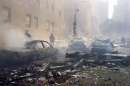 Cars smolder in the street as the destroyed World Trade Center burns in New York on September 11, 2001. Two hijacked commercial planes slammed into the twin towers of the World Trade Center Tuesday, causing both 110-story landmarks to collapse in thunderous clouds of fire and smoke.   REUTERS/Peter Morgan