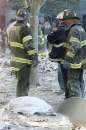 Firefighters stand near the remains of a person who died in the World Trade Center in New York on September 11, 2001. Two hijacked U.S. commercial planes slammed into the twin towers of the World Trade Center early on Tuesday, causing both 110-story landmarks to collapse in thunderous clouds of fire and smoke. REUTERS/Shannon Stapleton