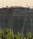 An American flag flies from the Pentagon September 12, 2001, while a firefighter sprays the fire still burning a day after a highjacked airliner crashed into the building. Three hijacked planes crashed into major U.S. landmarks September 11, destroying both of New York's mighty twin towers and plunging the Pentagon in Washington into flames, in an unprecedented assault on key symbols of U.S. military and financial power. REUTERS/Molly Riley