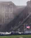 A lone American flag flies in front of the damaged area of the Pentagon building as firefighters and rescue workers continue to battle smoke at the U.S. military headquarters outside of Washington, September 12, 2001. The Pentagon and the World Trade Center buildings in New York City were attacked yesterday after terrorists hijacked commercial jetliners and crashed them into the buildings. Vertical dark line in image is a cable from a crane.  REUTERS/Larry Downing