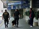 Atlanta police officers Daryl Tate (L) and Robert Roberts (C) of the K-9 unit patrol with their dog outside the terminal as a traveler (R) who did not wish to be identified talks on a cell phone outside the Hartsfield International Airport terminal in Atlanta, Georgia, which was closed on September 12, 2001. All flights in the United States were grounded after attacks in New York City and Washington on September 11, 2001.  REUTERS/Tami Chappell