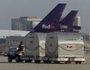 A Federal Express employee moves empty cargo containers on the tarmac at Los Angeles International Airport with two parked FedEx jets idle in background, September 12, 2001. Due to the shutdown of the United States air traffic system, FedEx has been severely affected, as it moves several million packages daily in the United states. Several of the airplanes which crashed into the New York World Trade Center and The Pentagon in Washington September 11 were bound for Los Angeles. REUTERS/Fred Prouser