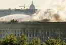 The Pentagon continues to burn September 12, 2001, a day after a hijacked airliner crashed into the building. The U.S. Capitol is seen in the background across the Potomac River. (Molly Riley/Reuters)