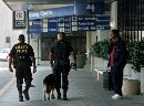 Atlanta police officers Daryl Tate (L) and Robert Roberts (C) of the K-9 unit patrol with their dog as a traveler talks on a cell phone outside a terminal at Hartsfield International Airport in Atlanta, Georgia, which was closed early on September 12, 2001. All flights in the United States were grounded after attacks in New York City and Washington on September 11, 2001. (Tami Chappell/Reuters)